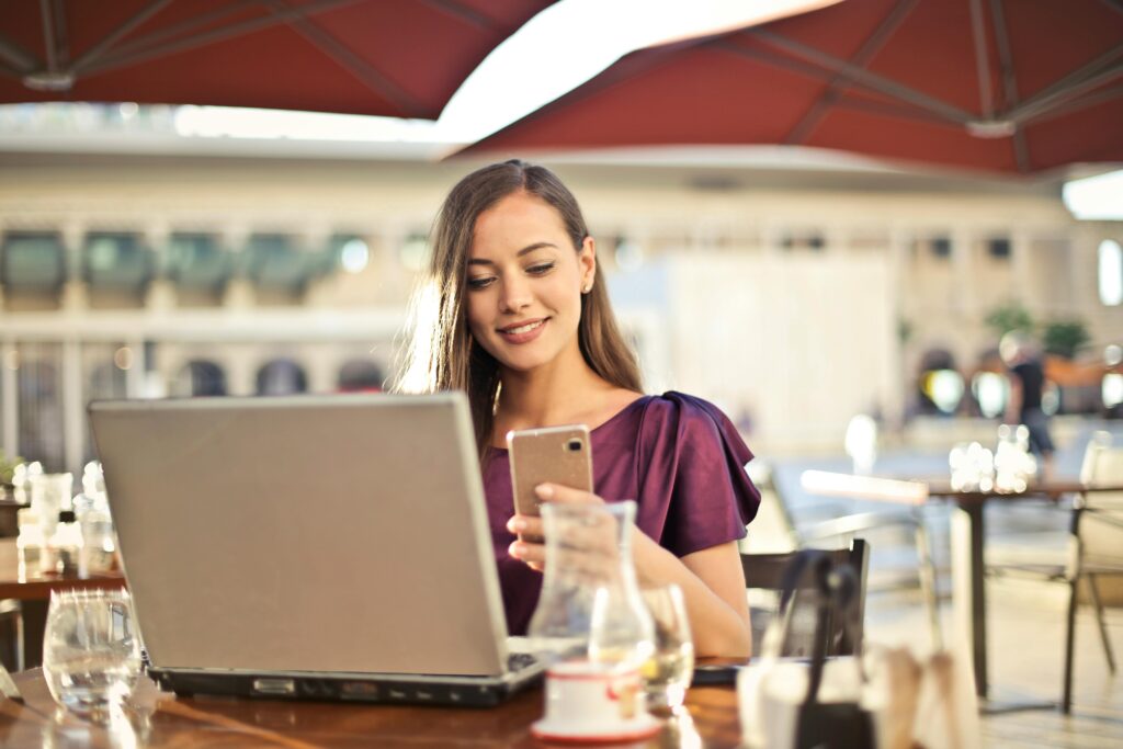 pexels photo 826349 826349 Woman enjoying remote work at a café, using a laptop and smartphone.