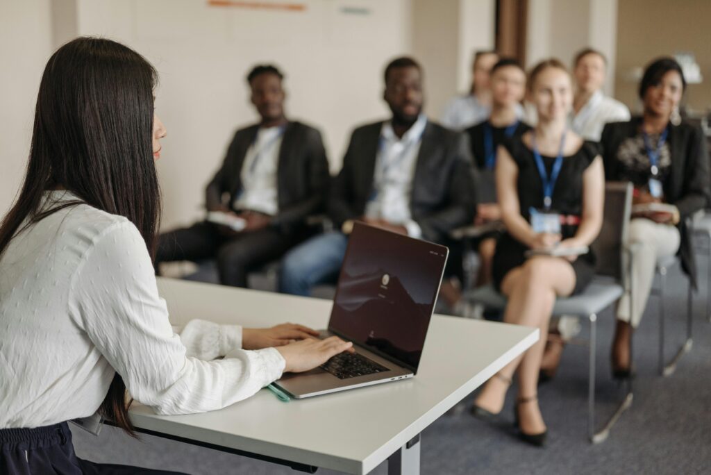 pexels photo 8761533 8761533 Professional woman giving a presentation to a diverse group of colleagues in an office.